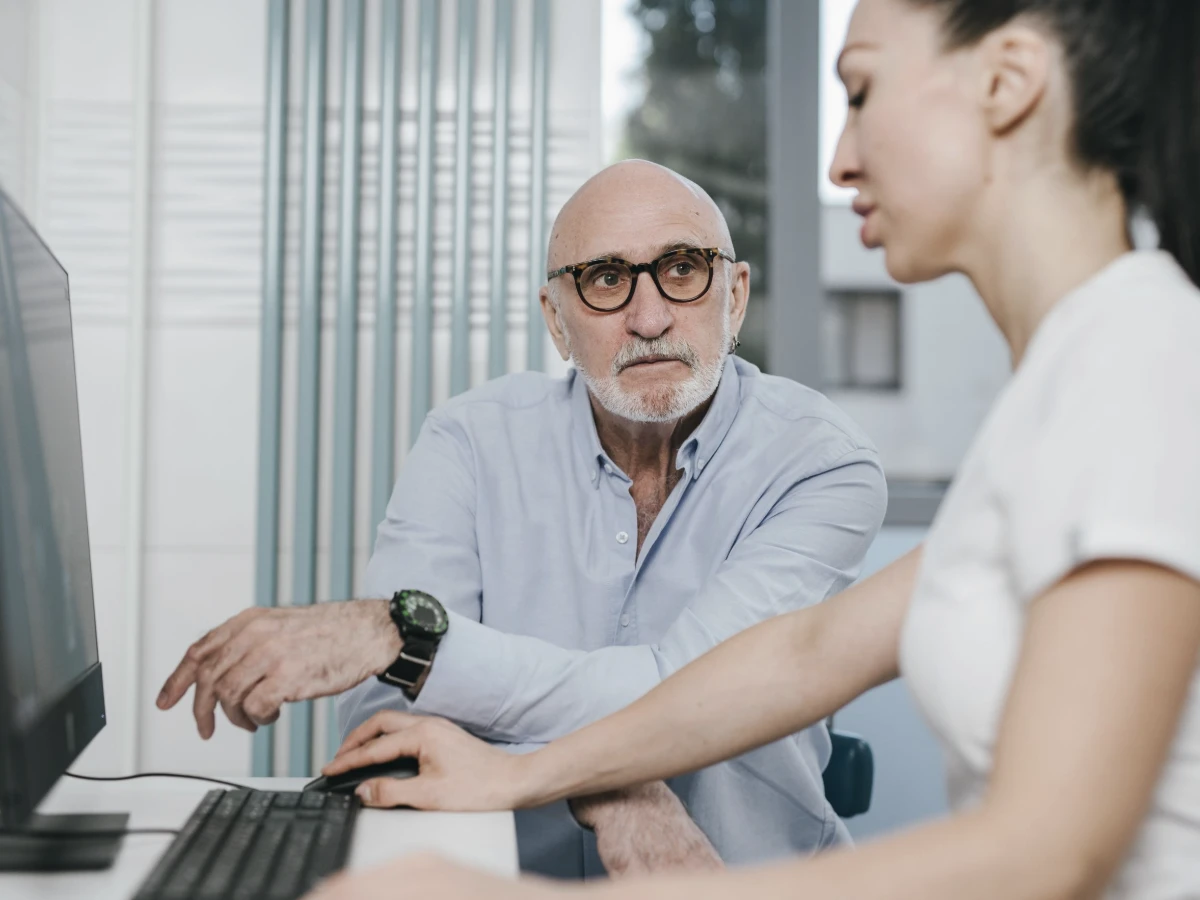 An older man reviewing results with a clinician at a screen