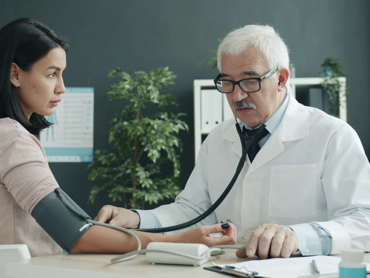 A doctor measuring a patient’s blood pressure with a cuff in a clinic