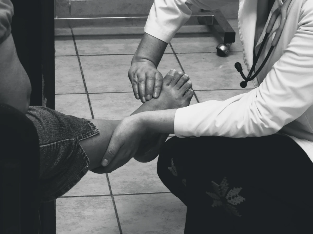 A clinician examining a patient’s bare foot during a consultation