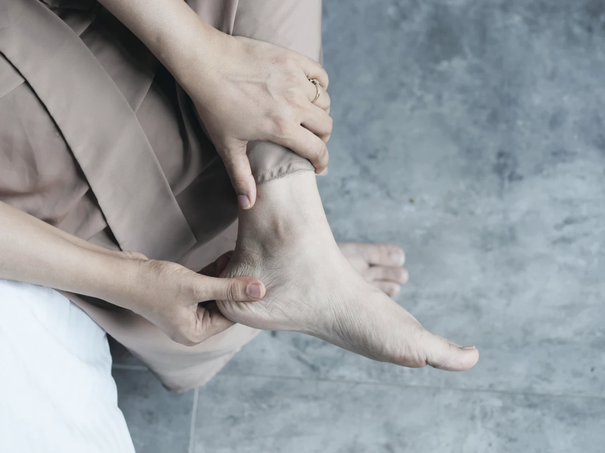 Two hands turning a bare foot to check the sole and edges for damage