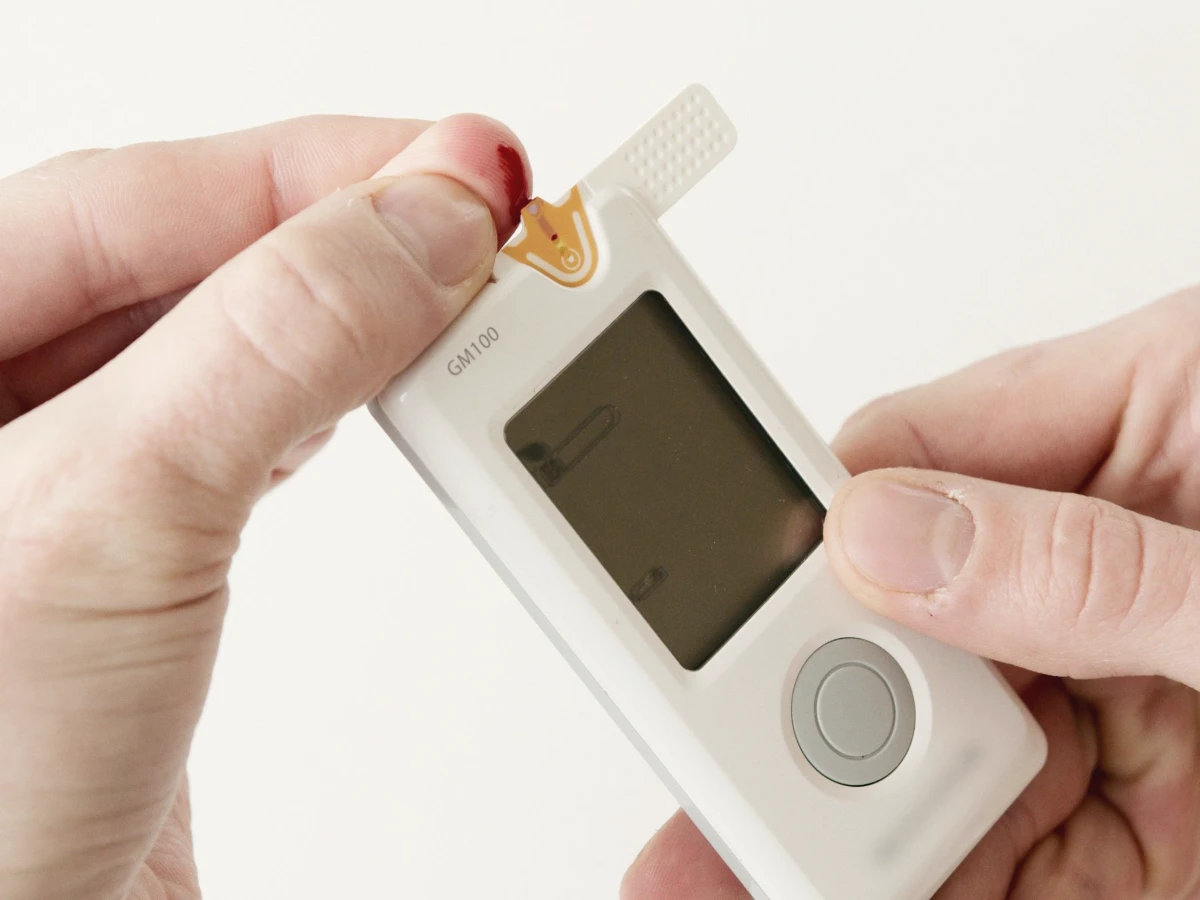Hands using a glucose meter to check a blood sugar reading