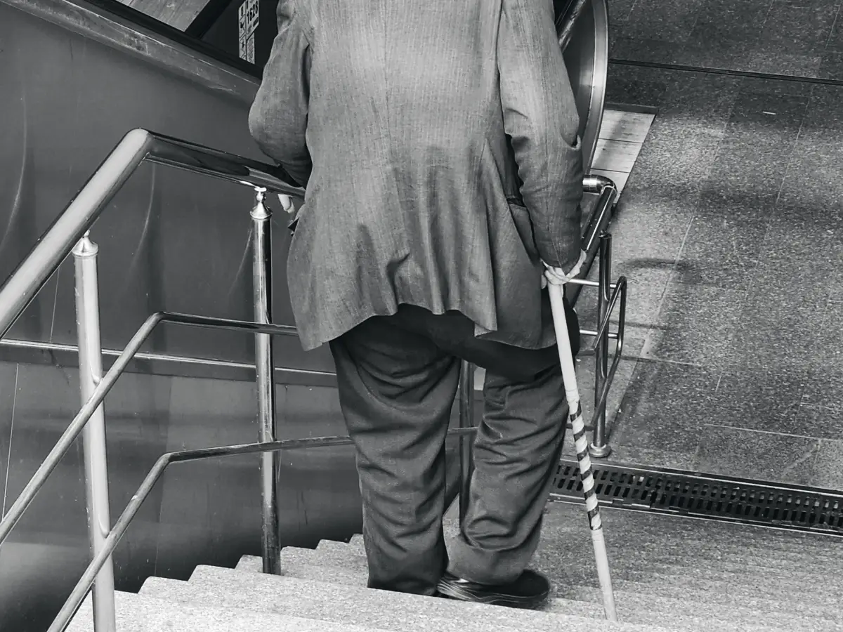 An older man using a walking cane to go down a flight of steps