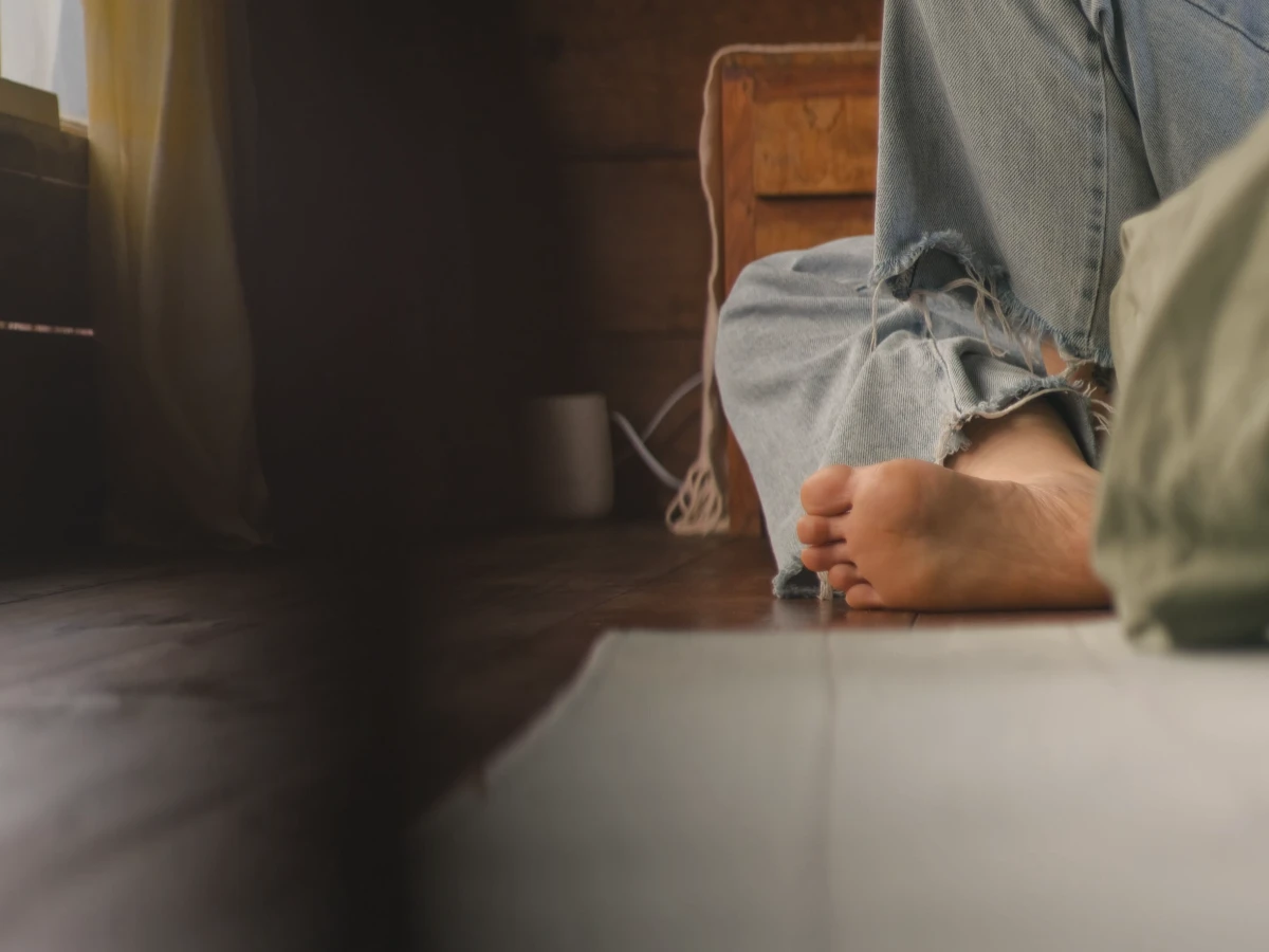Bare feet resting on a wooden floor in a quiet room at home