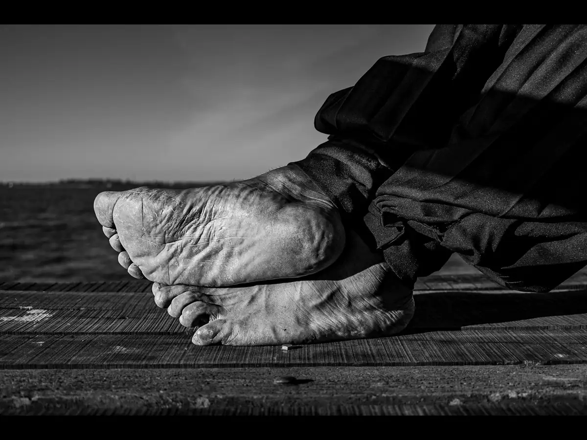 Black and white close-up of two bare feet resting on a wooden surface