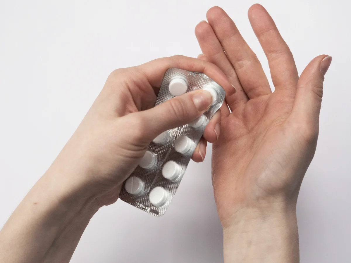 Hands holding a blister pack of white tablets