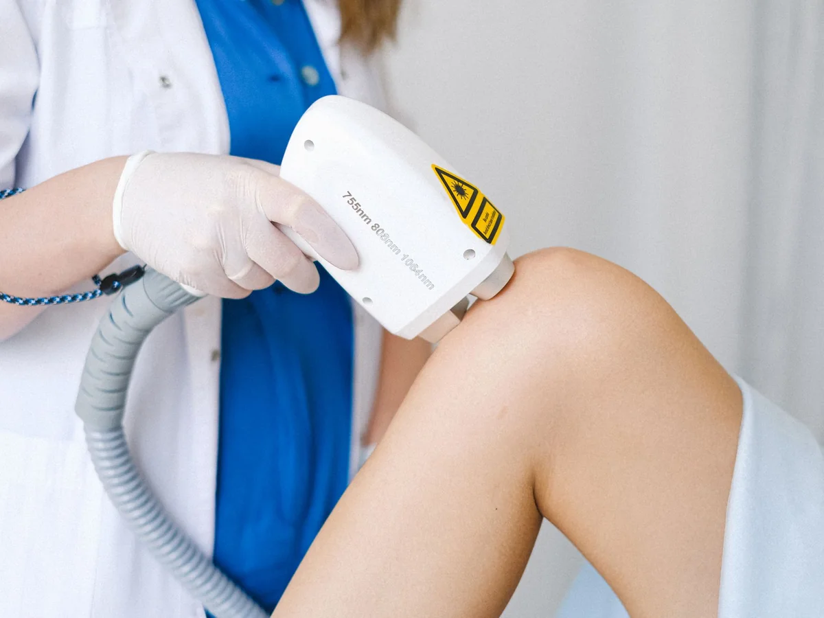 A clinician holding a low-level laser therapy device against a patient’s knee
