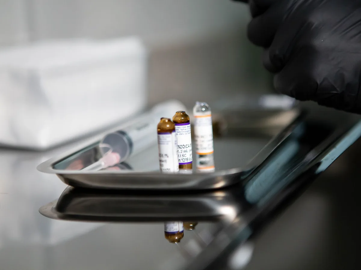 Opened medical vials and a syringe on a stainless steel tray in a clinic
