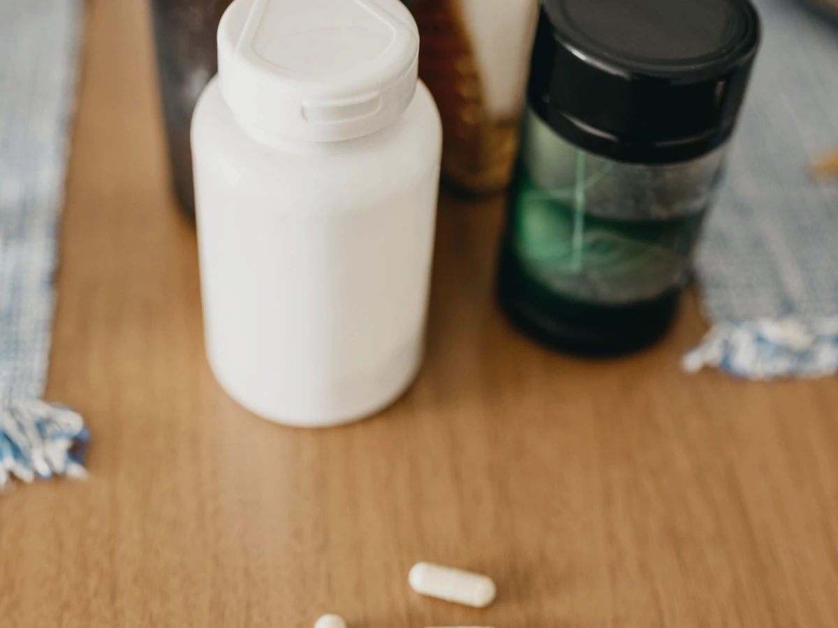 Several supplement bottles and loose capsules on a wooden surface