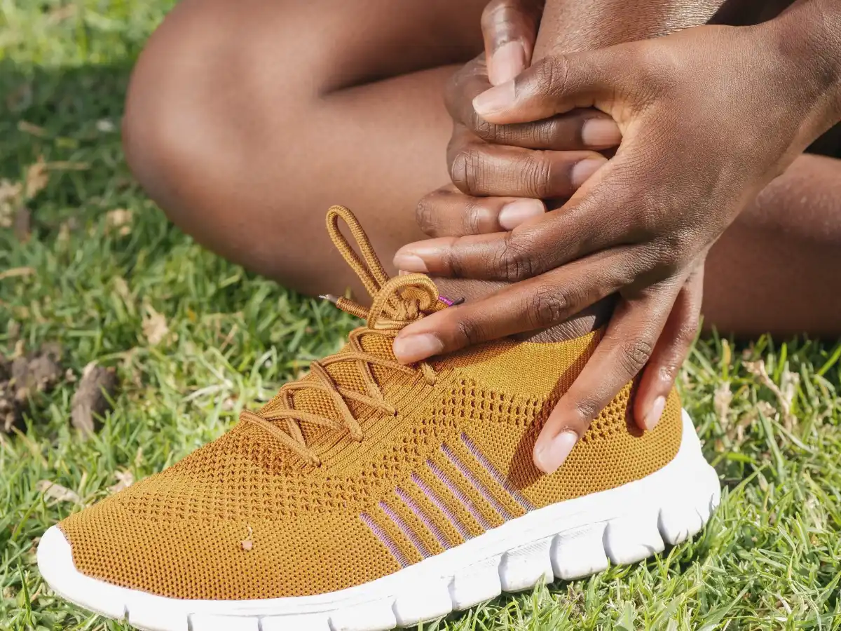 A person holding the inner side of their ankle