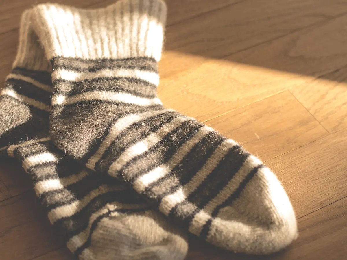 Thick striped wool socks on a sunlit wooden floor
